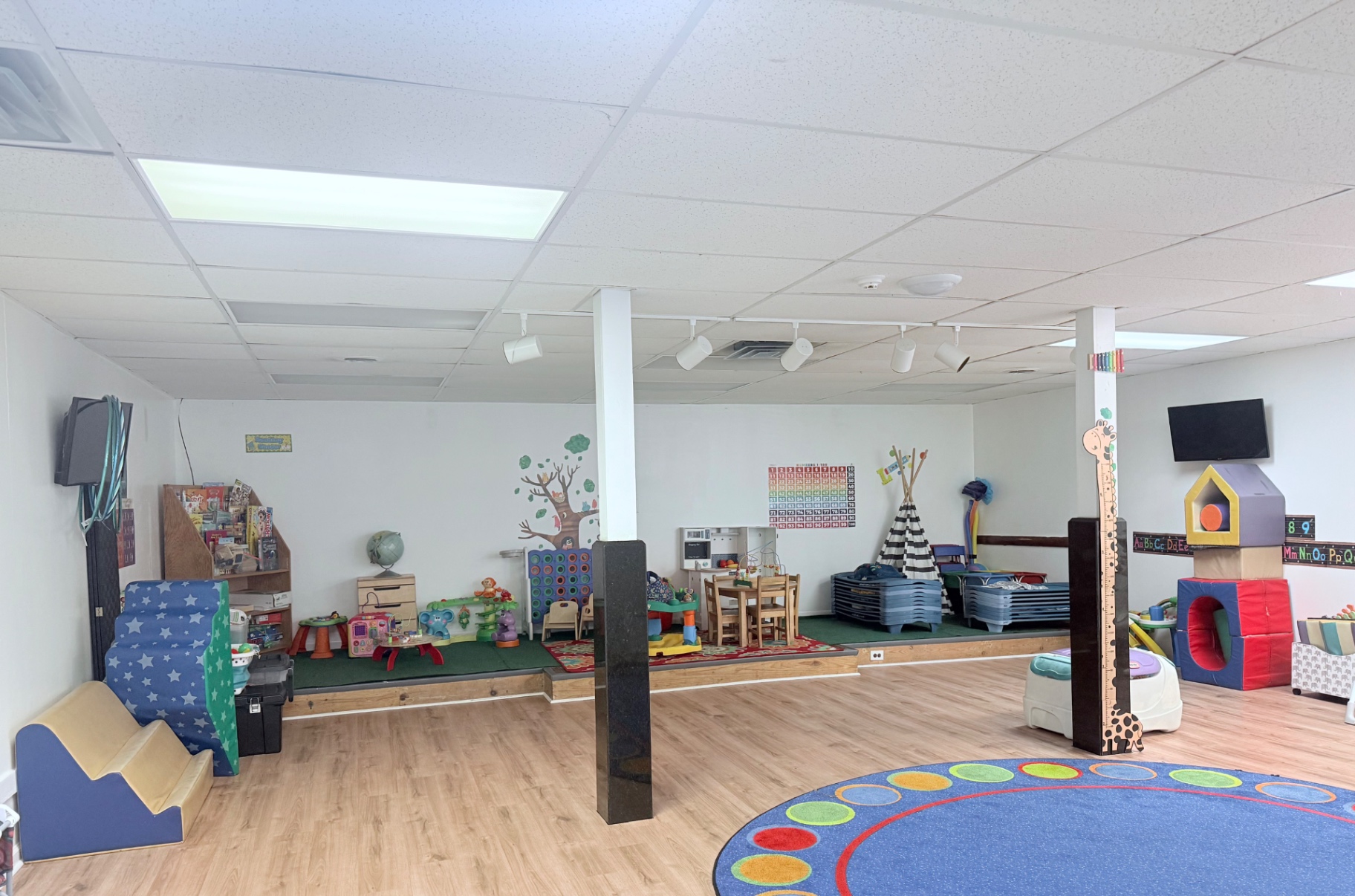 Bright open learning room at Eastwood with reading nook, play stations, and a circle-time rug
