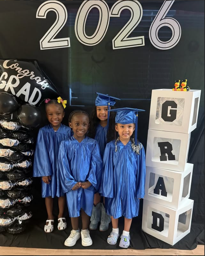 Eastwood preschool graduates in blue caps and gowns in front of the 2026 GRAD backdrop